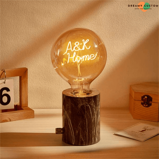 Una cálida y elegante bombilla de filamento personalizada con un mensaje luminoso único, montada en una base de mármol con estilo. Un regalo original y significativo para bodas o aniversarios.