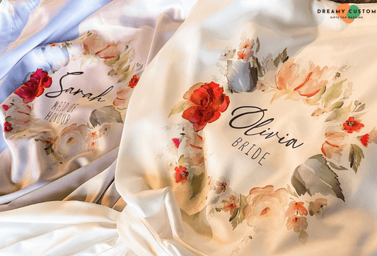 Luxurious satin bridal robes adorned with elegant floral designs and personalized names. A perfect blend of sophistication and sentiment, ideal for the bride and bridal party to cherish on the wedding day.
