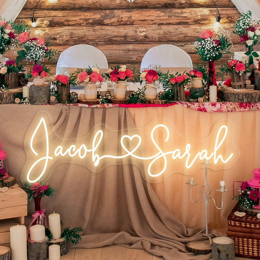 A beautifully illuminated custom neon sign featuring the couple's names adds a romantic glow to the wedding décor. Perfect for a sweetheart table or reception backdrop, creating a warm and personalized ambiance.