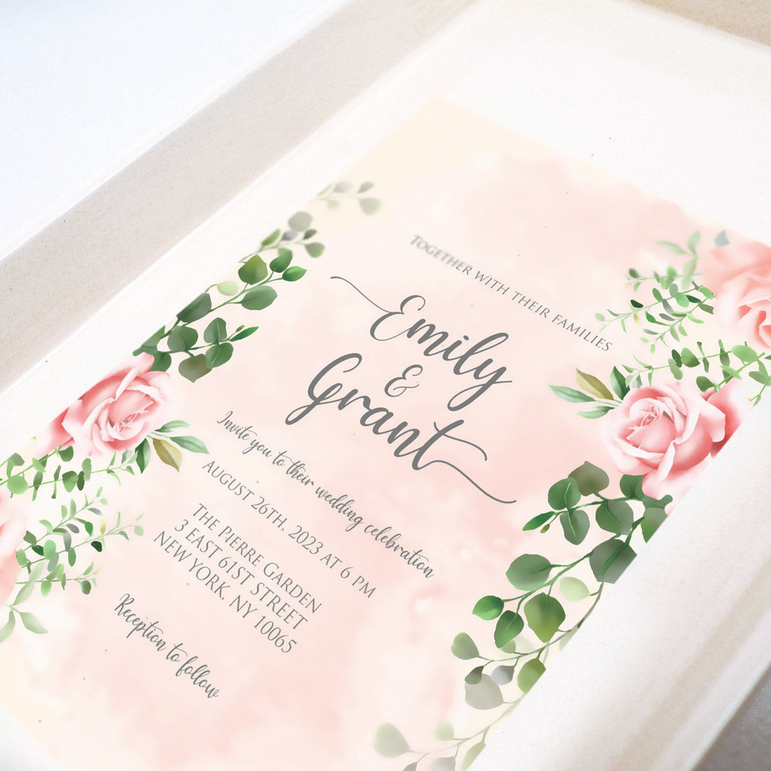 Elegant floral wedding invitation with pink roses and greenery, showcasing names, date, and venue—perfect for setting a romantic tone and pairing with themed dessert trays that tell your love story.