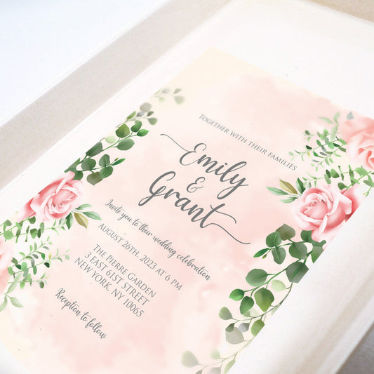 Elegant floral wedding invitation with pink roses and greenery, showcasing names, date, and venue—perfect for setting a romantic tone and pairing with themed dessert trays that tell your love story.