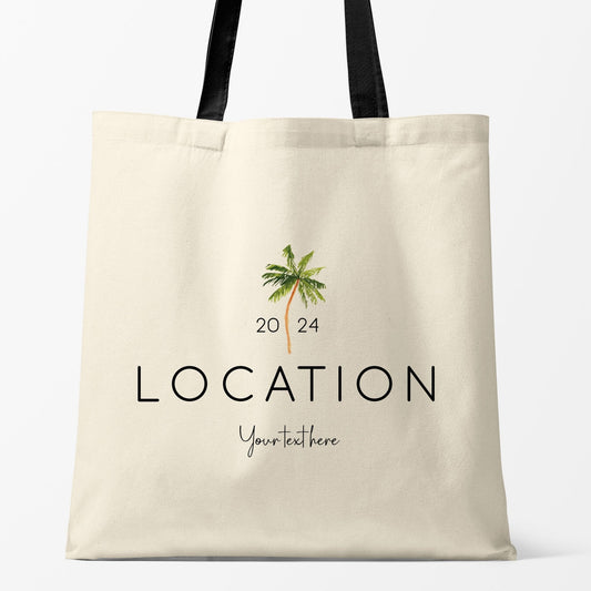 The image displays a customizable beach tote bag with a palm tree design. The text "LOCATION 2024" is featured prominently, with a space for personalized text, making it ideal for destination weddings or events.