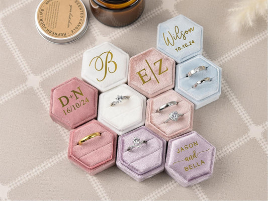 A selection of personalized velvet ring boxes, showcasing different colors and designs. Each box is engraved with custom initials, dates, or names, making them a perfect keepsake for engagements and proposals.
