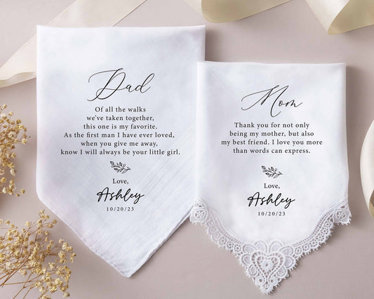 A pair of personalized wedding handkerchiefs with heartfelt messages from Ashley to both Mom and Dad. The handkerchiefs feature delicate lace details and a soft floral design, dated October 20, 2023.
