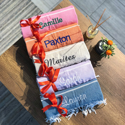 A close-up image of custom beach towels with personalized names, featuring colorful towels tied with red ribbons.