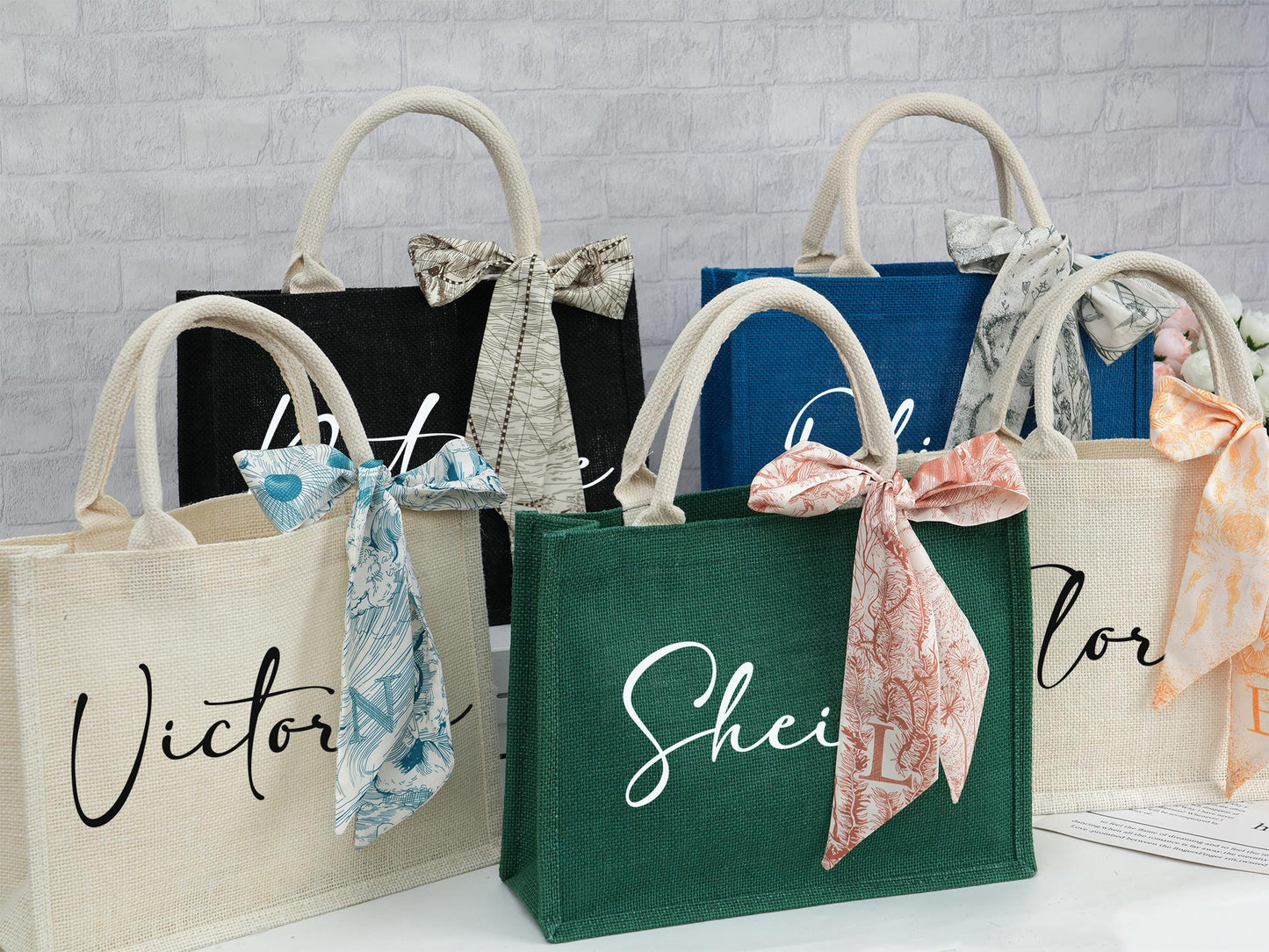 Personalized burlap tote bags in black, blue, green, and white, featuring different name fonts and matching ribbons.
