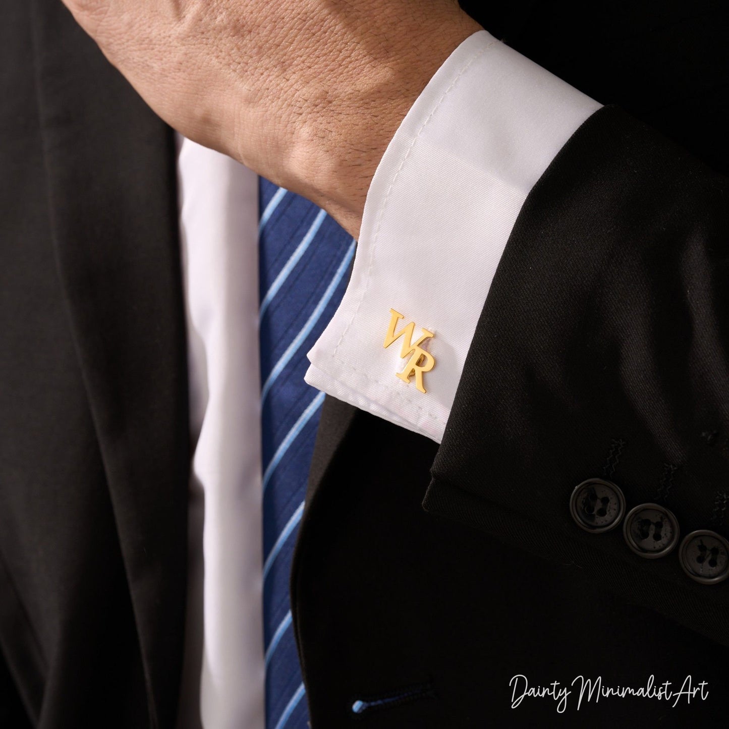 A businessman wearing gold initial cufflinks on a formal suit.