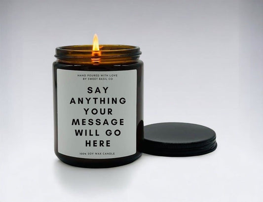 A lit amber jar personalized wedding candle with a label reading "Say Anything Your Message Will Go Here," hand-poured by Sweet Basil Co, displayed with its lid on a white background.