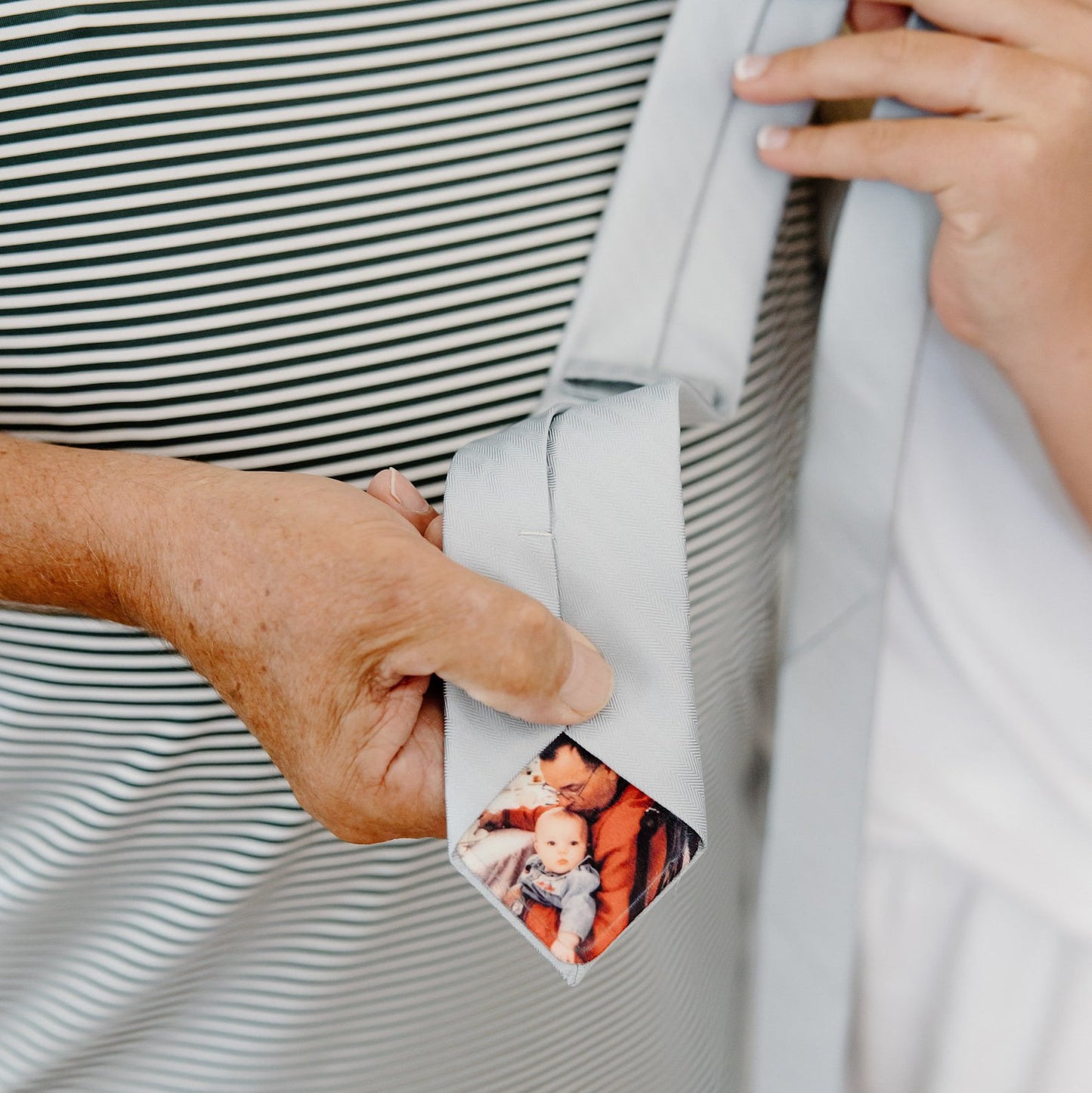 Bride holding customized tie with hidden photo patch featuring a precious father and child moment