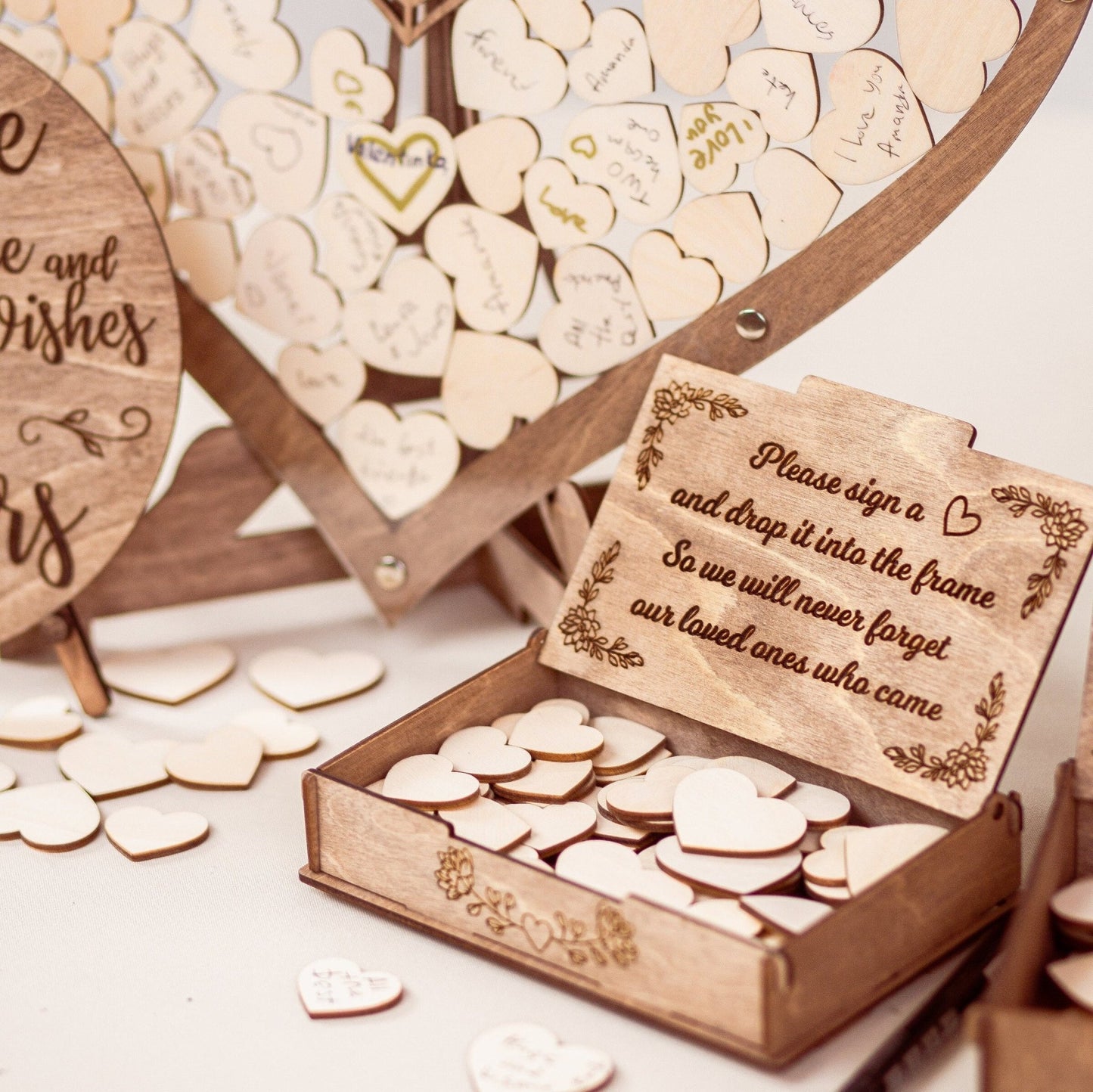 Close-up of a personalized wedding guest book with wooden hearts and an engraved keepsake box.