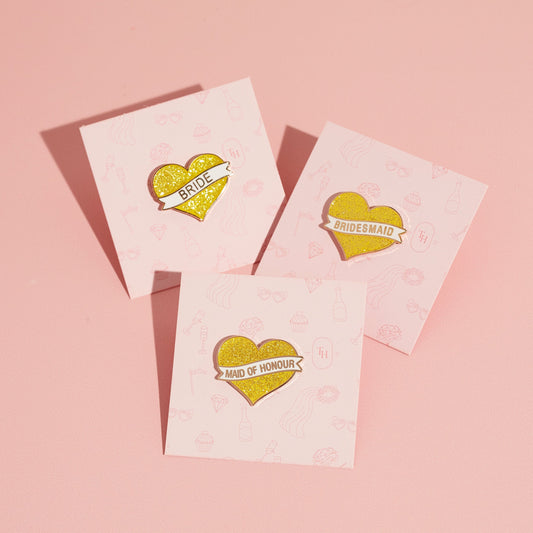 Bridesmaid proposal gift lapel pins with glittery gold heart design.