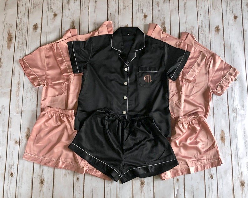 Elegant flat lay of personalized satin short pajama set in black and pink with monogrammed initials
