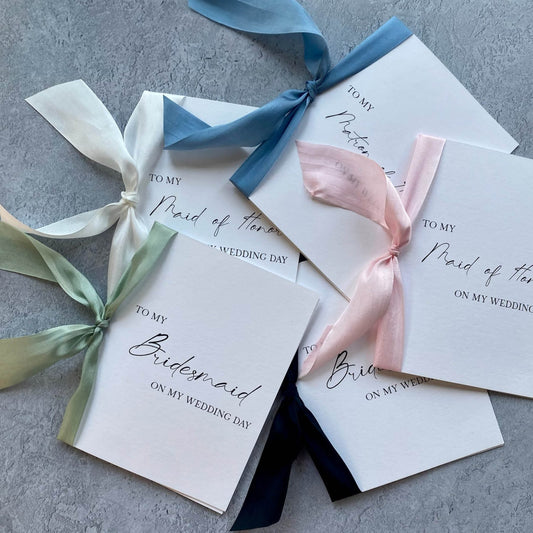 Elegant white maid of honor proposal cards with pastel ribbons tied in bows