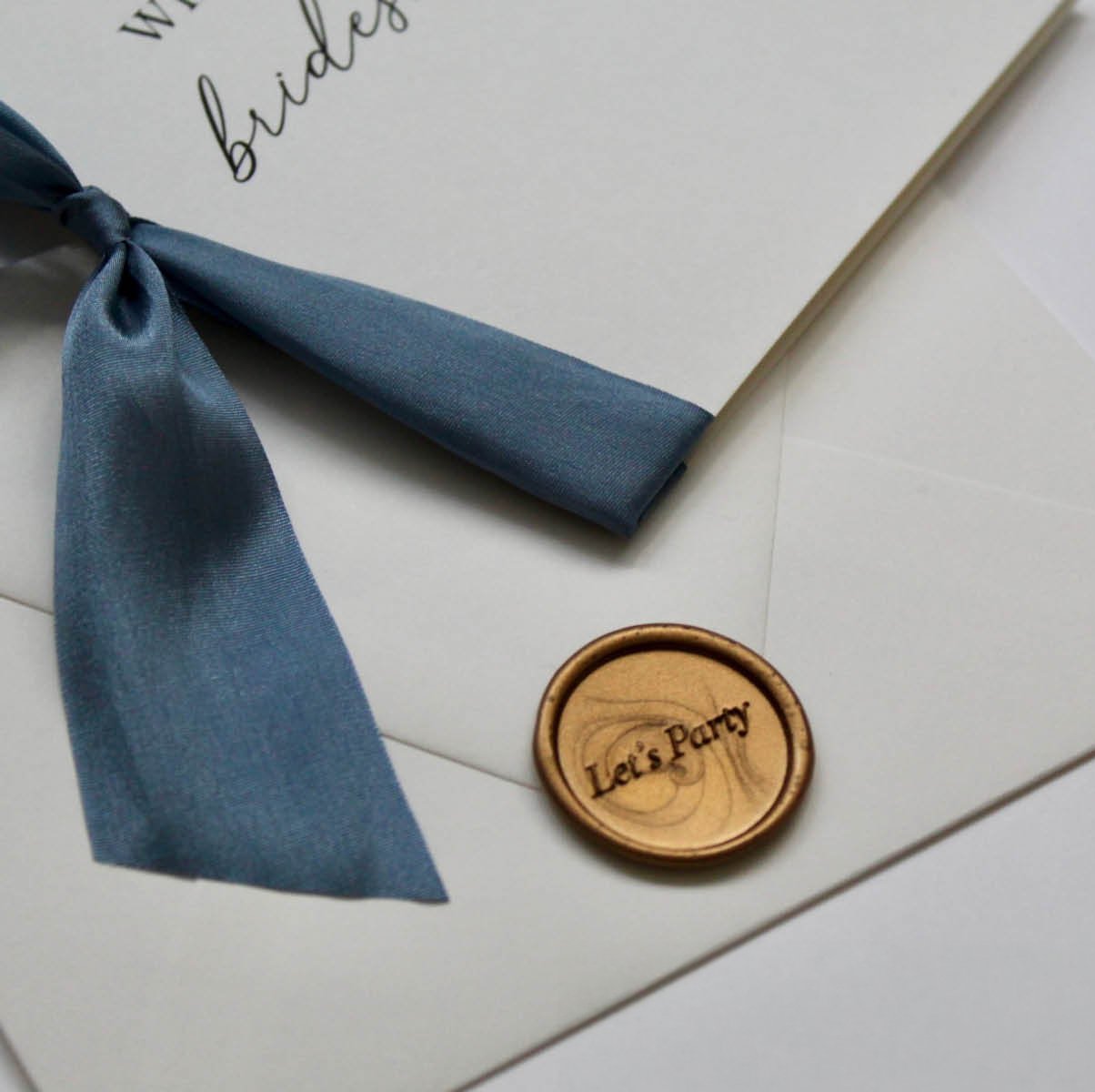 Gold wax seal and blue ribbon on a white proposal card for bridesmaids