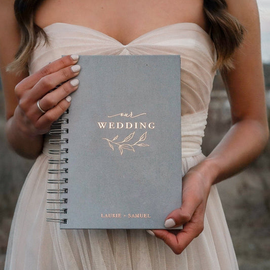 Elegant wedding planner organizer book cover in soft gray with gold embossed "WEDDING" text.