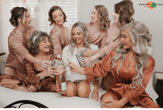 The bride and her bridal party share a joyful toast in matching satin robes, celebrating the special day with laughter and love. A heartfelt pre-wedding moment filled with warmth and excitement.