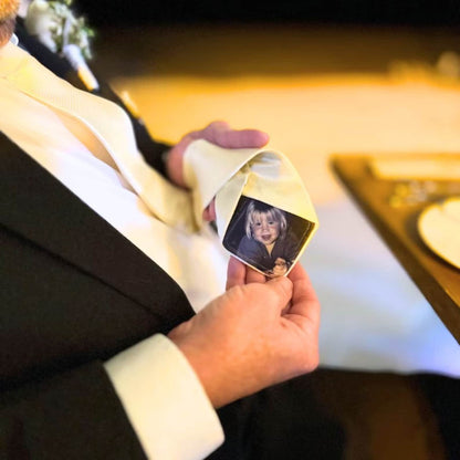 Father-holding-a-cream-colored-tie-with-a-custom-photo-tie-patch-displaying-a-child's-photo.
