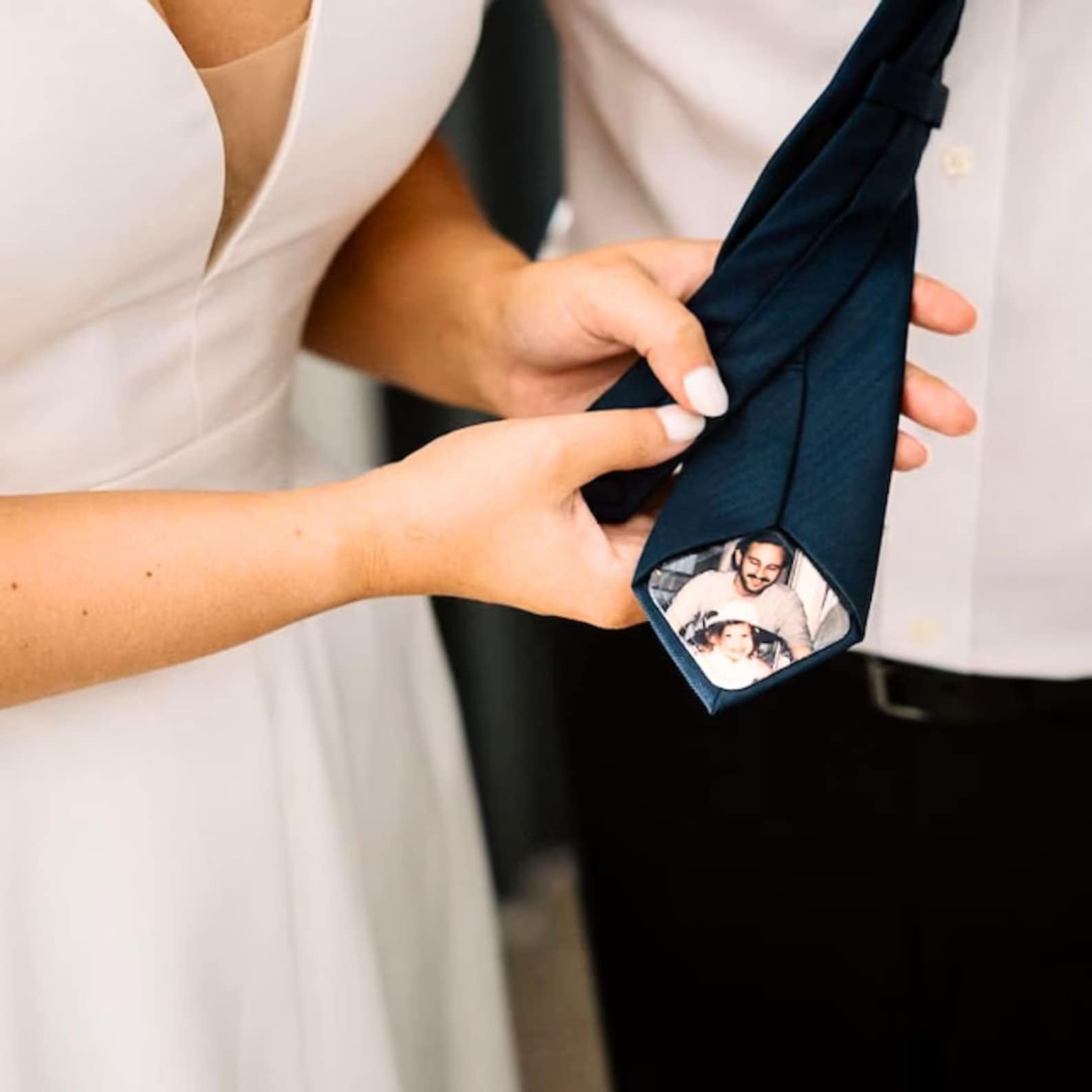 Bride-and-groom-holding-a-navy-tie-with-a-custom-photo-tie-patch-featuring-a-father-and-baby.