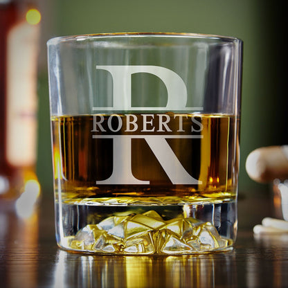 Close-up view of personalized whiskey glass engraved with large initial "R" and surname "Roberts," featuring a unique glacier-style base.