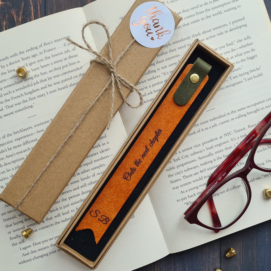 Orange leather bookmark with foil embossed text, designed for an elegant reading experience.