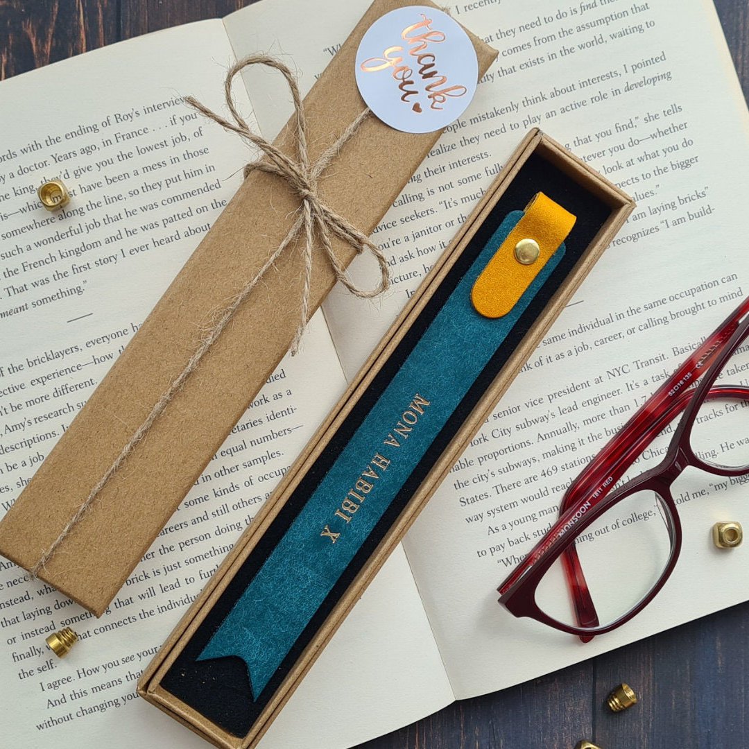 Brown leather bookmark with engraved text and decorative stitching, ideal for book lovers.