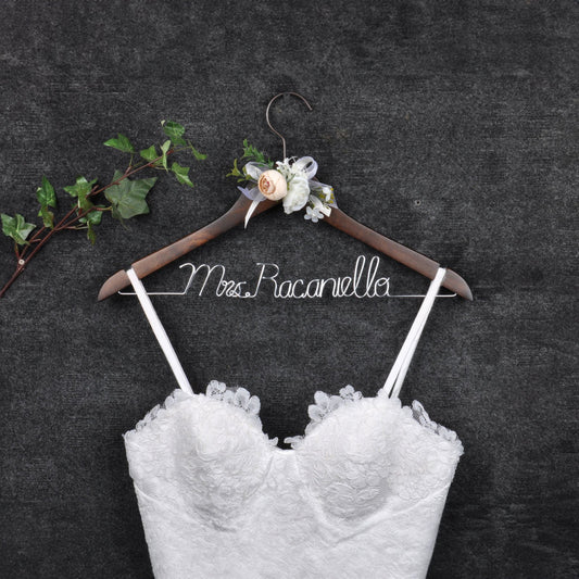 Personalized bridal gown hanger with custom name in silver wire, featuring floral decorations.