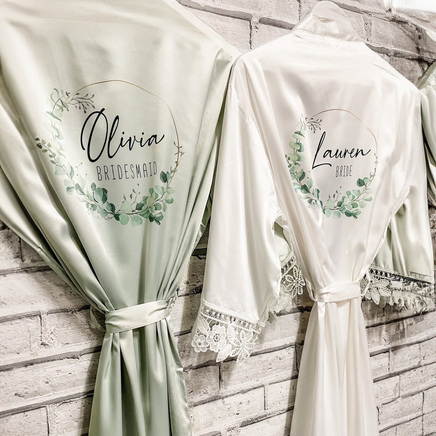 Custom sage green bridesmaid robes: Elegant sage green satin robes with personalized names 'Olivia' and 'Lauren' in a wreath design, perfect for bridal prep.