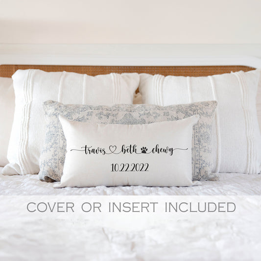 Personalized wedding kneeling pillow with custom names and date, displayed on a white bed.