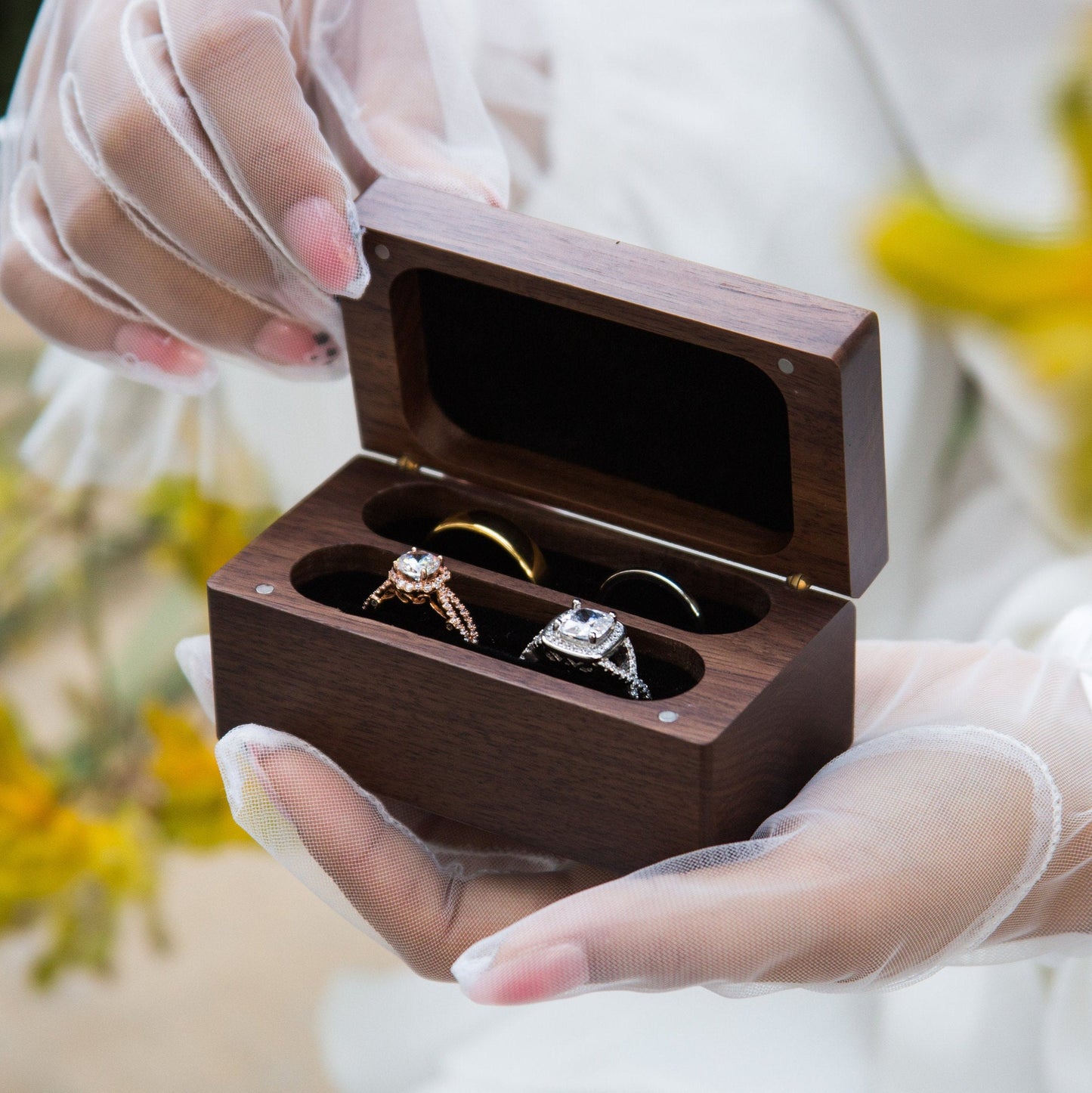 Open wooden ring box displaying wedding rings